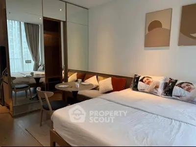 Modern bedroom with cozy seating area and mirrored wardrobe in stylish apartment.