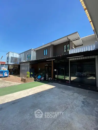 Modern industrial-style building with spacious parking area and clear blue sky.