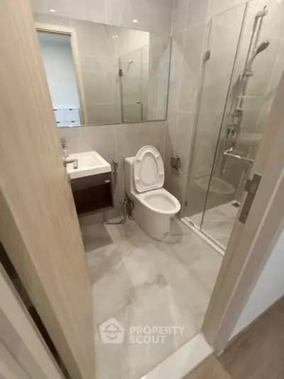 Modern bathroom with glass shower and sleek fixtures in a contemporary apartment.