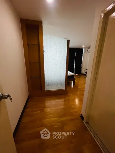 Cozy bedroom with wooden flooring and modern glass partition in a stylish apartment.