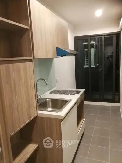 Modern kitchen with sleek cabinetry and glass sliding doors leading to balcony.