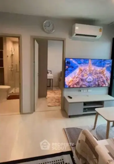 Modern living room with wall-mounted TV and air conditioning, adjacent to a stylish bathroom.