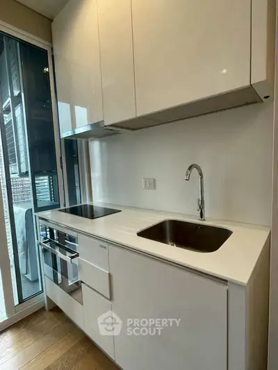 Modern kitchen with sleek white cabinetry and stainless steel appliances in a contemporary apartment.