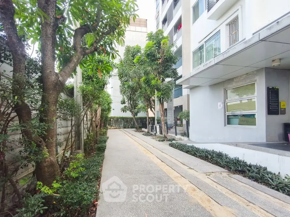 Modern apartment building with lush garden pathway and contemporary design.