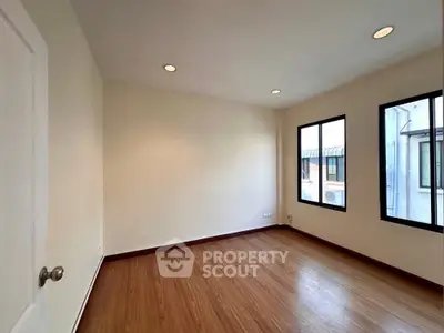 Spacious and well-lit empty room with polished hardwood flooring and multiple windows offering ample natural light, ideal for a personalized living space.