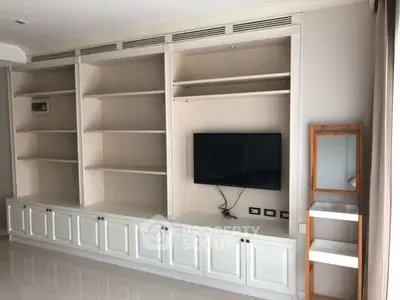 Spacious living room with built-in shelves and mounted TV, perfect for modern living.