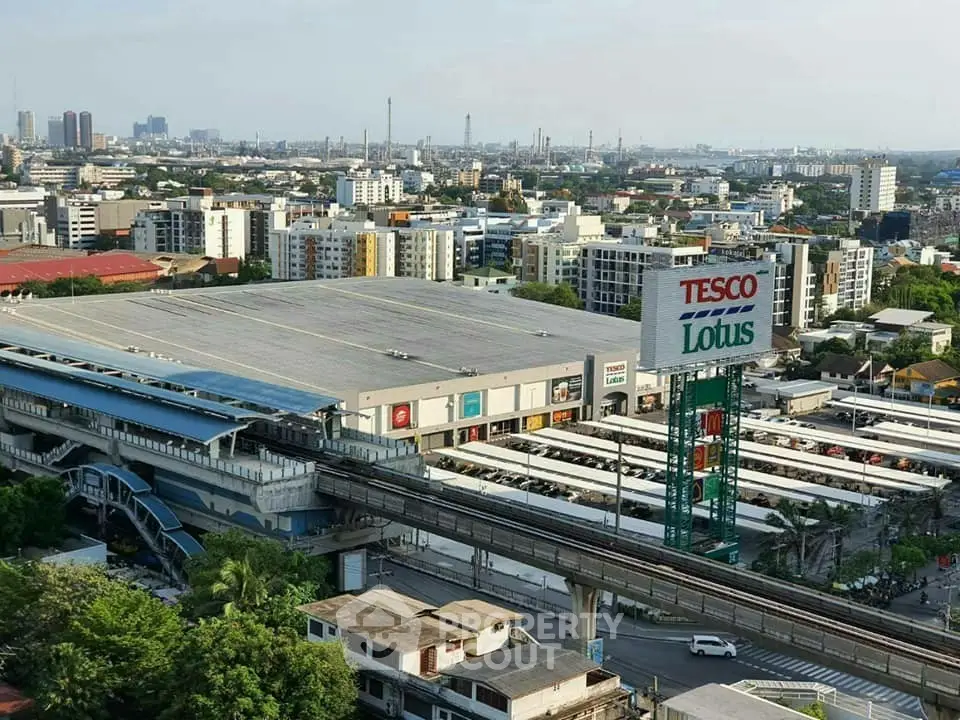 Aerial view of a bustling urban area with a prominent Tesco Lotus shopping center and surrounding buildings.