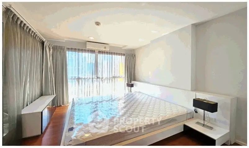 Spacious bedroom with large windows and modern decor, perfect for natural light lovers.