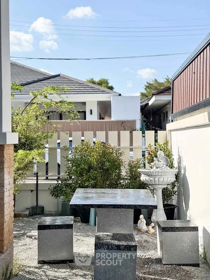 Charming outdoor garden area with modern stone table and seating, perfect for relaxation and entertaining.