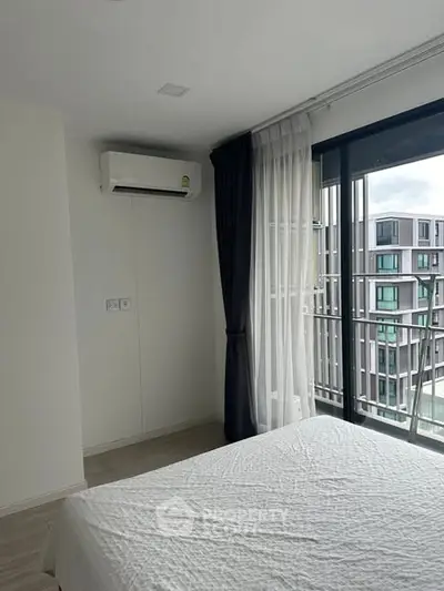 Modern bedroom with large window and city view, featuring air conditioning and elegant curtains.