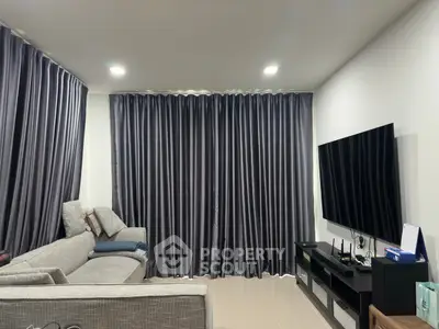 Modern living room with sleek gray sofa and large flat-screen TV, perfect for relaxation and entertainment.