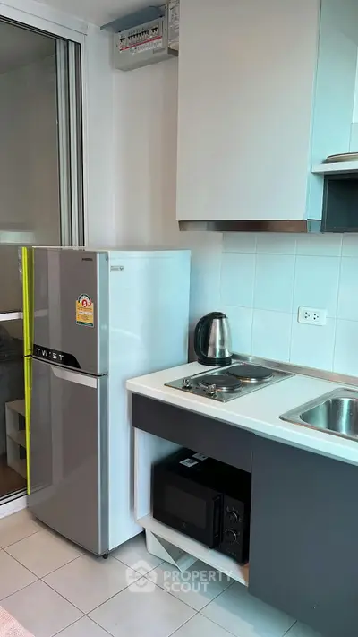 Modern compact kitchen with stainless steel appliances and sleek cabinetry in a contemporary apartment.