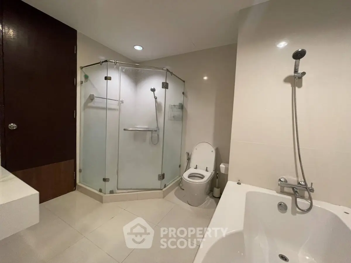 Modern bathroom with glass shower and bathtub in a sleek apartment.