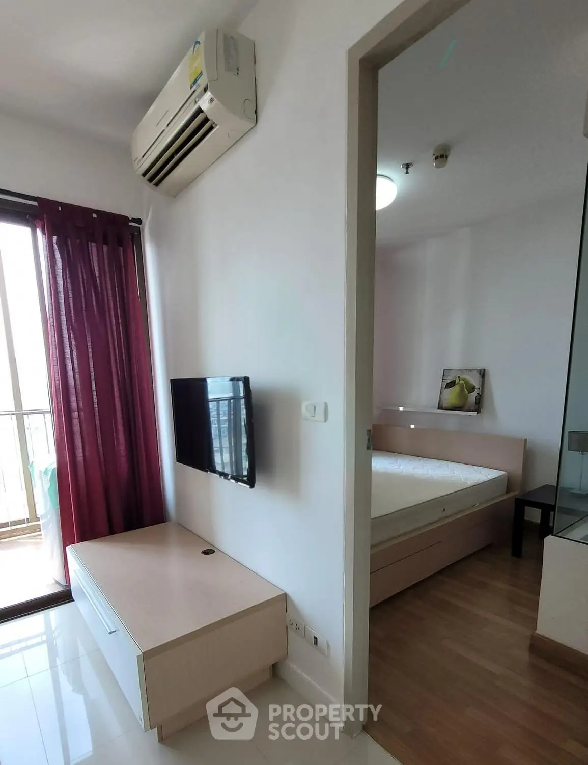 Modern apartment interior with air conditioning, wall-mounted TV, and cozy bedroom with balcony access.
