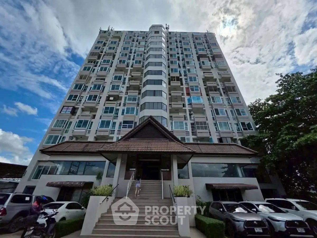 Modern high-rise condominium building with unique architectural design and ample parking space.