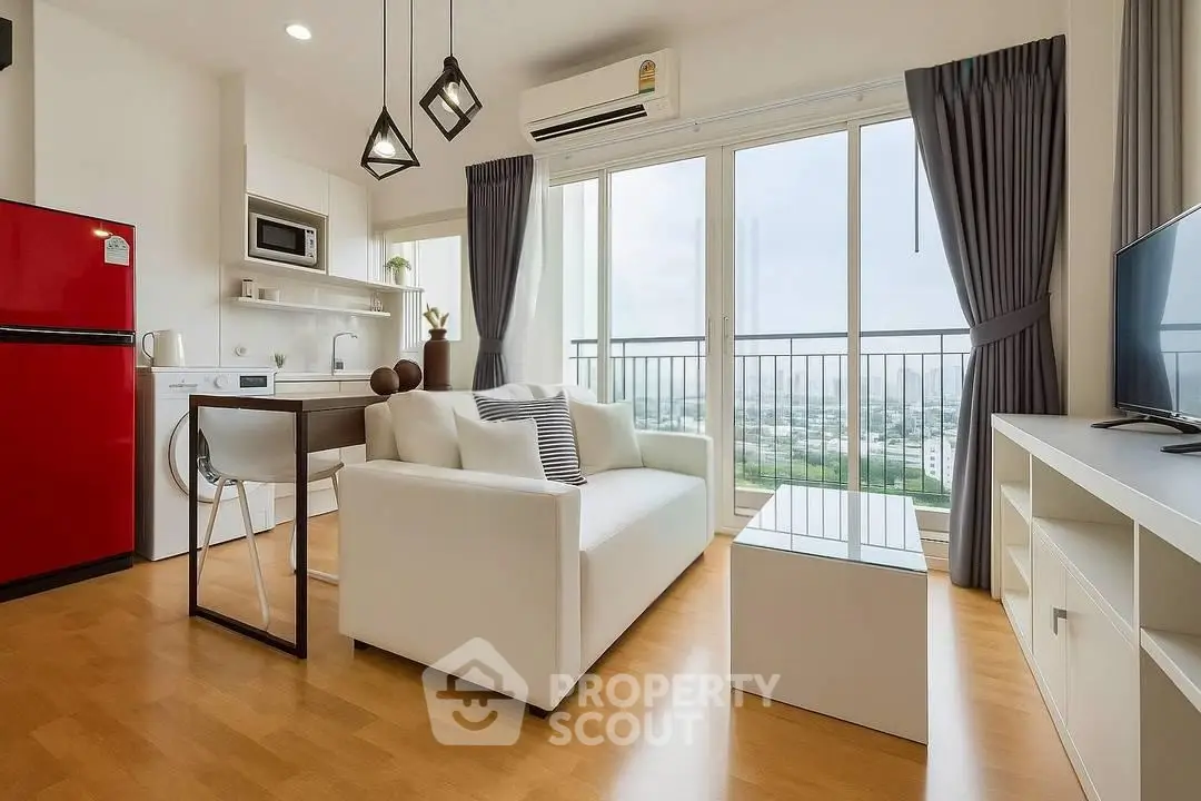 Modern living room with open kitchen, red fridge, and city view balcony in a stylish apartment.