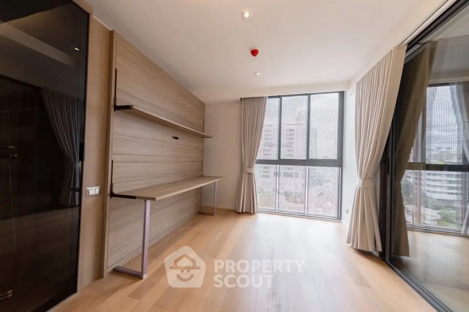 Spacious modern room with large windows and wooden flooring in a high-rise apartment.