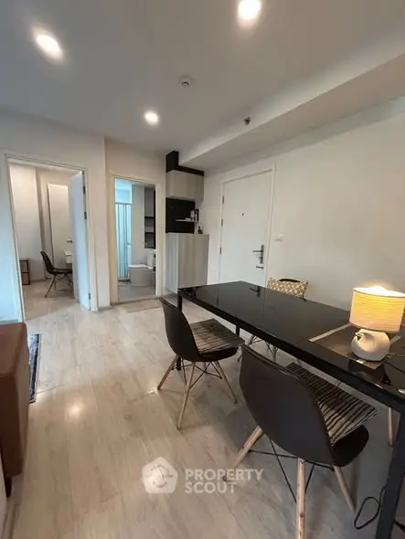 Modern dining area with sleek black table and stylish chairs in open-plan apartment.