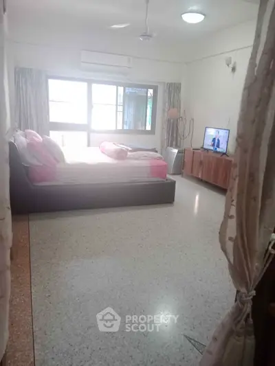 Spacious bedroom with large windows and modern furnishings in a bright apartment.