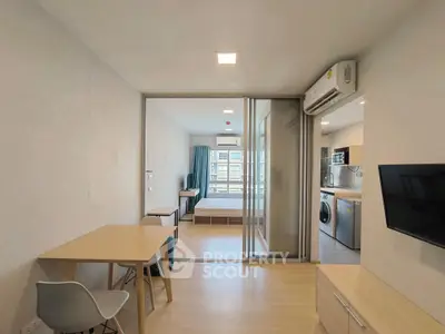 Modern apartment interior with open layout, featuring a kitchen, dining area, and bedroom.