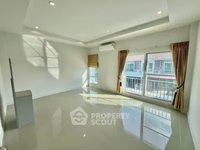 Spacious sunlit living room with large windows and modern ceiling lights.