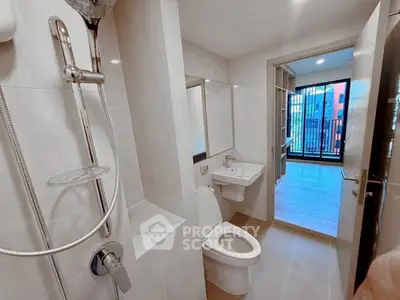 Modern bathroom with sleek fixtures and view into a bright room with balcony access.