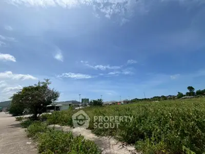 Expansive land plot with lush greenery under a clear blue sky, ideal for development opportunities.