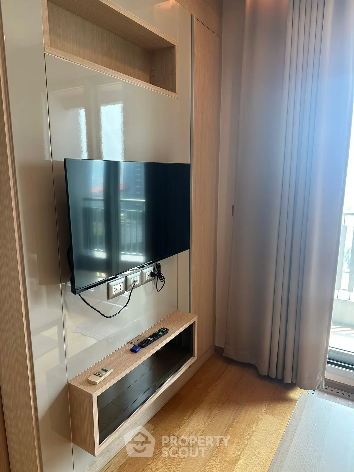 Modern living room with wall-mounted TV and balcony view