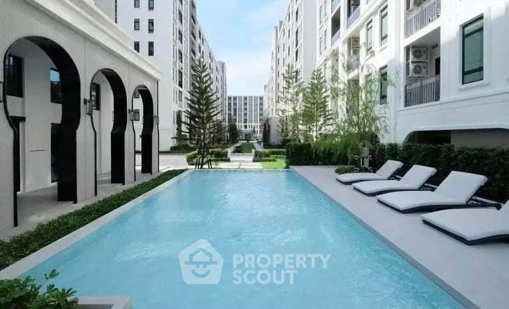 Luxurious apartment complex with a pristine swimming pool and elegant architecture.