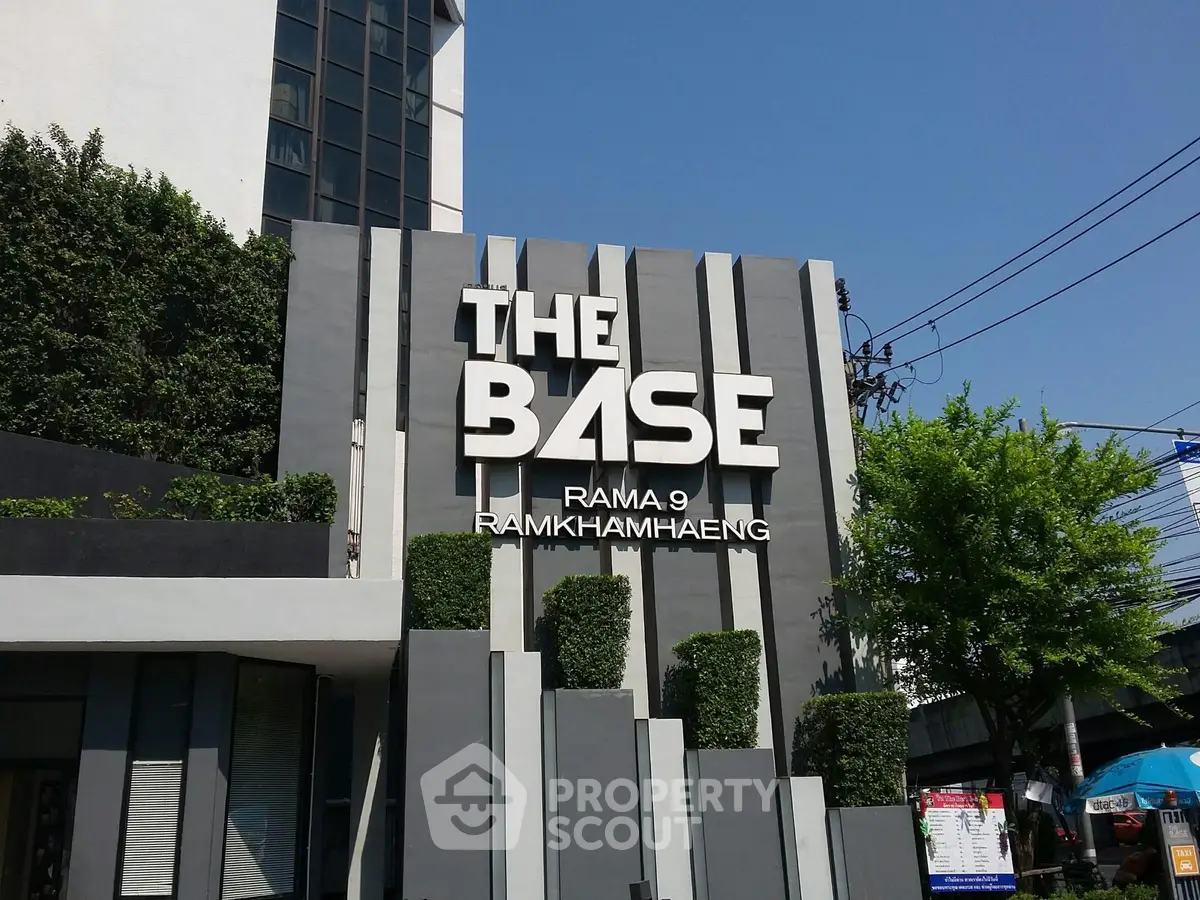 Modern building entrance with stylish signage and lush greenery