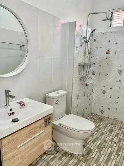 Modern bathroom with stylish fixtures and unique tile design, featuring a round mirror and sleek vanity.