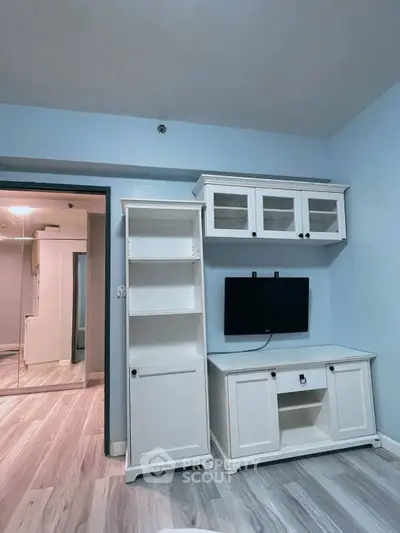 Modern living room with stylish white furniture and mounted TV, featuring sleek wooden flooring.