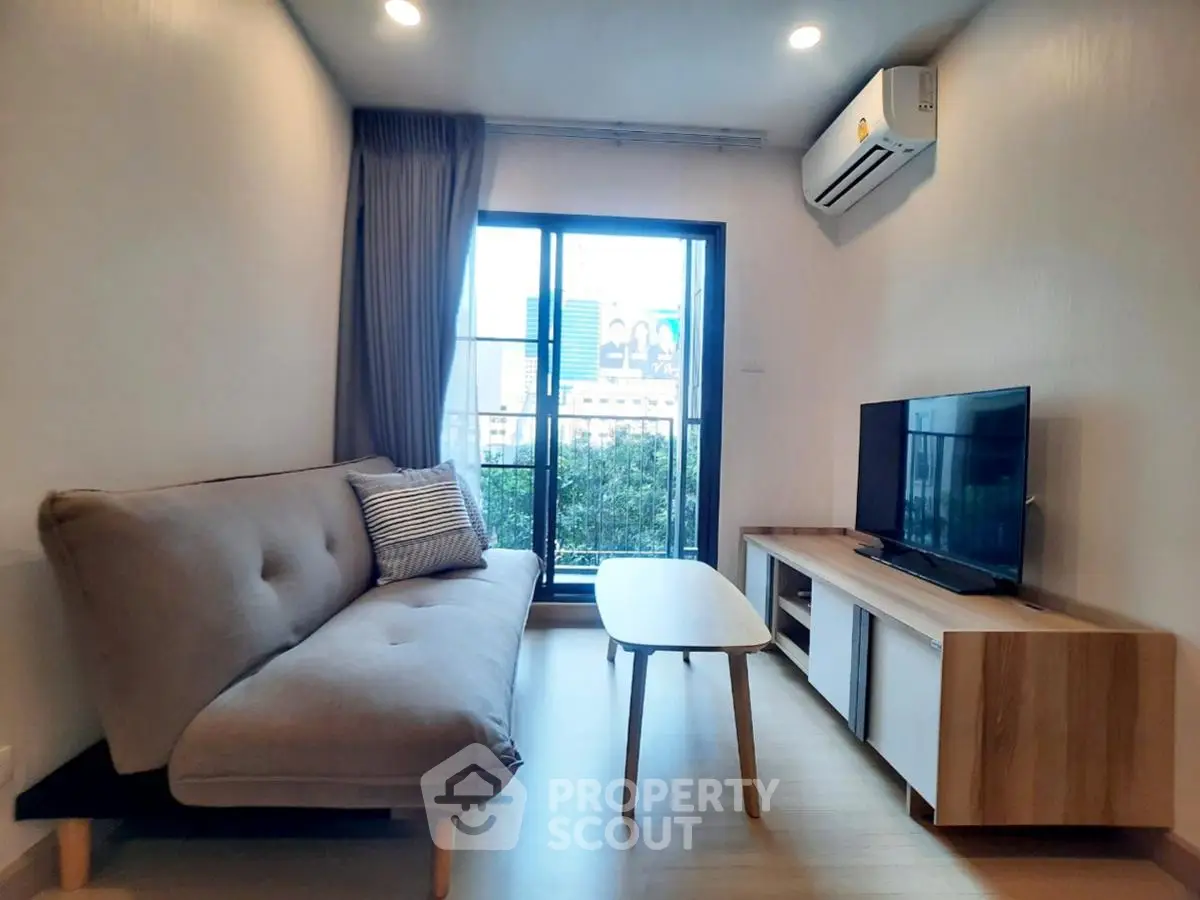 Modern living room with sleek furniture and large window offering city view.