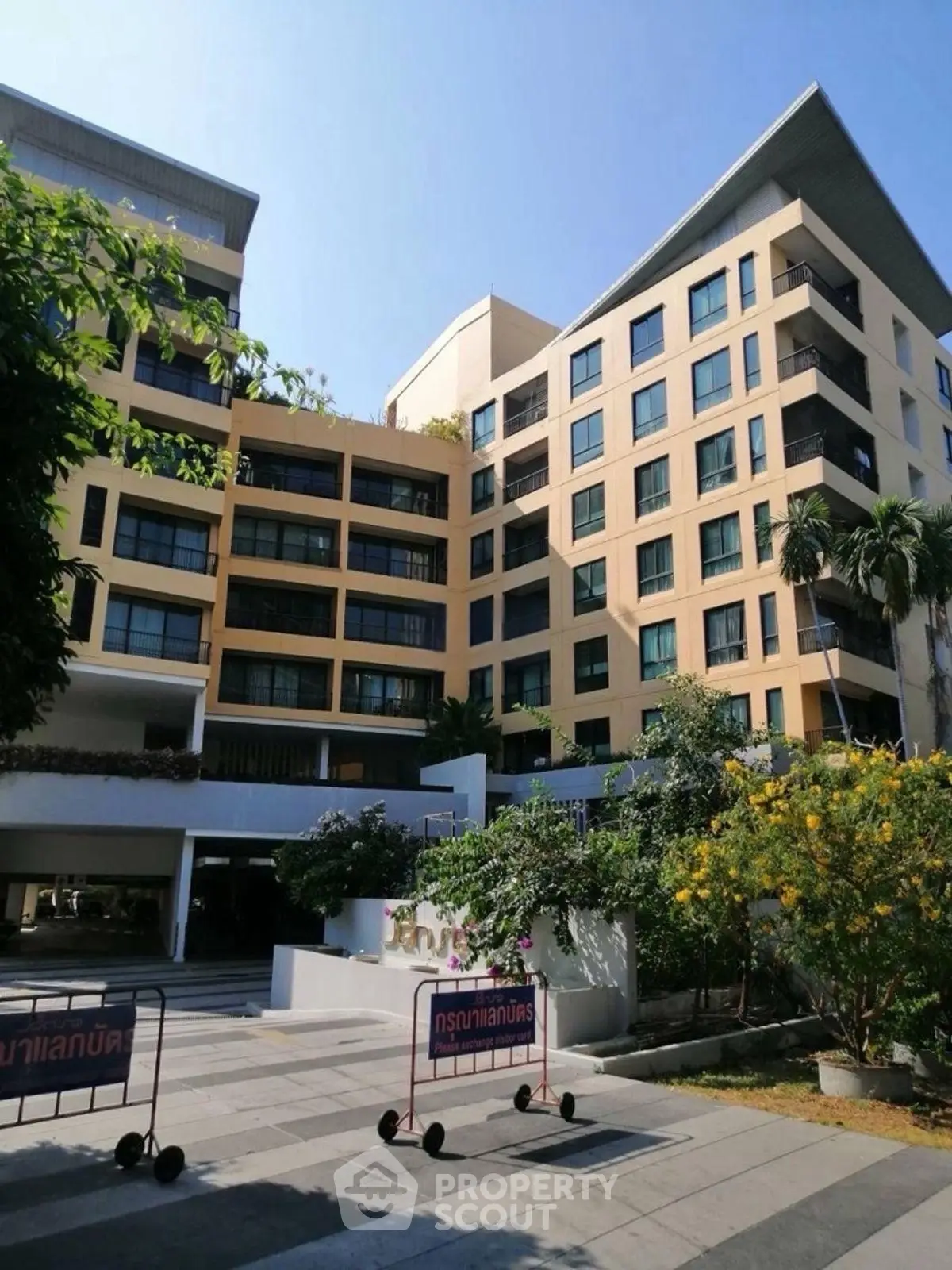 Modern multi-story residential building with lush landscaping and spacious outdoor area.