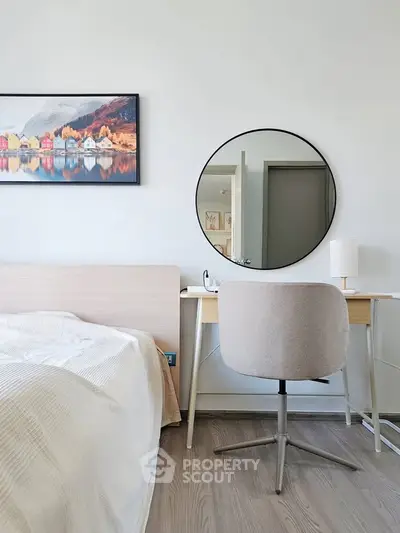 Modern bedroom with stylish decor, featuring a cozy bed, sleek desk, and elegant round mirror.
