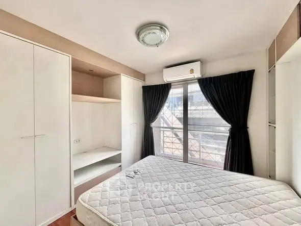 Bright bedroom with large window and built-in storage in modern apartment.