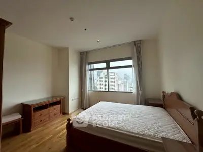 Spacious bedroom with city view and wooden furniture in modern apartment