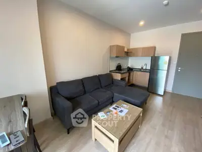 Modern living room with cozy sofa and compact kitchen in open layout apartment.