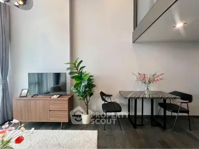 Modern living room with stylish furniture and high ceiling, featuring a TV stand, dining table, and indoor plant.
