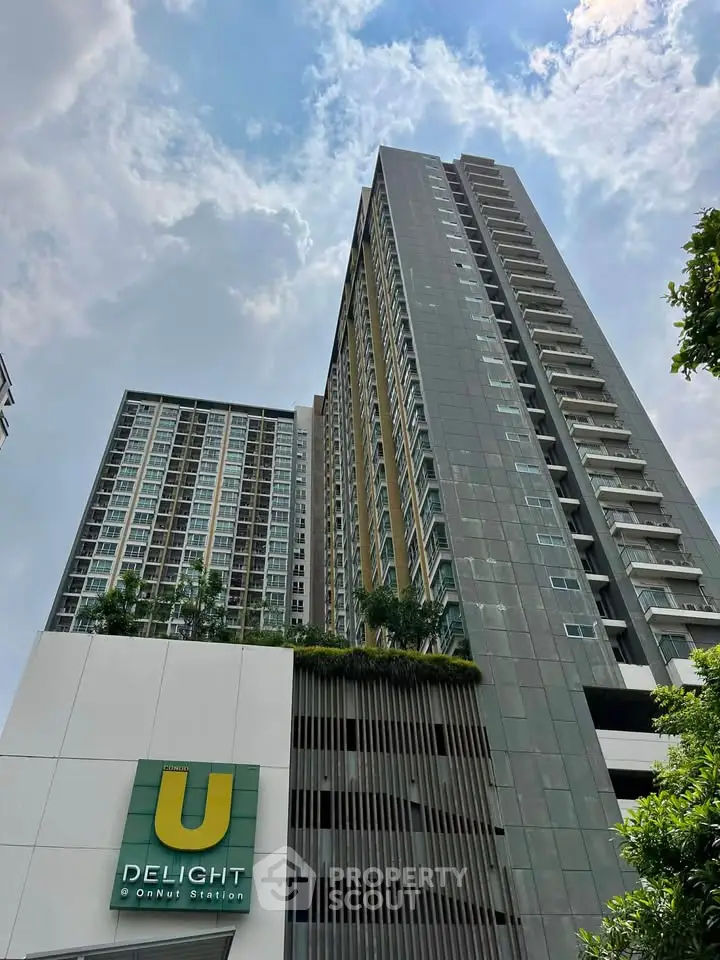 Modern high-rise condominium with lush greenery and urban skyline view.