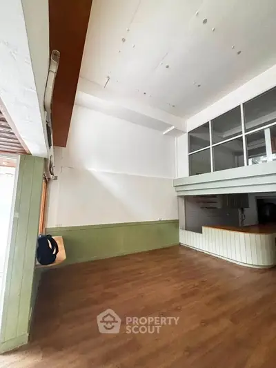 Spacious interior with high ceilings and wooden flooring, featuring a mezzanine and open layout kitchen.