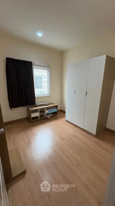 Spacious bedroom with wooden flooring and ample natural light.