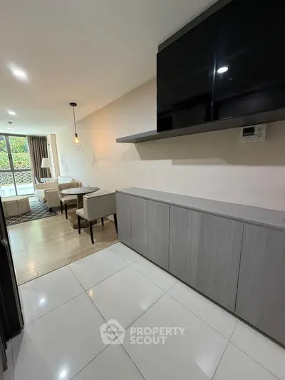 Modern living room with sleek cabinetry and stylish dining area, featuring large windows for natural light.