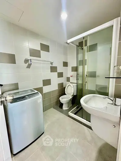 Modern bathroom with washing machine and shower enclosure in stylish apartment.