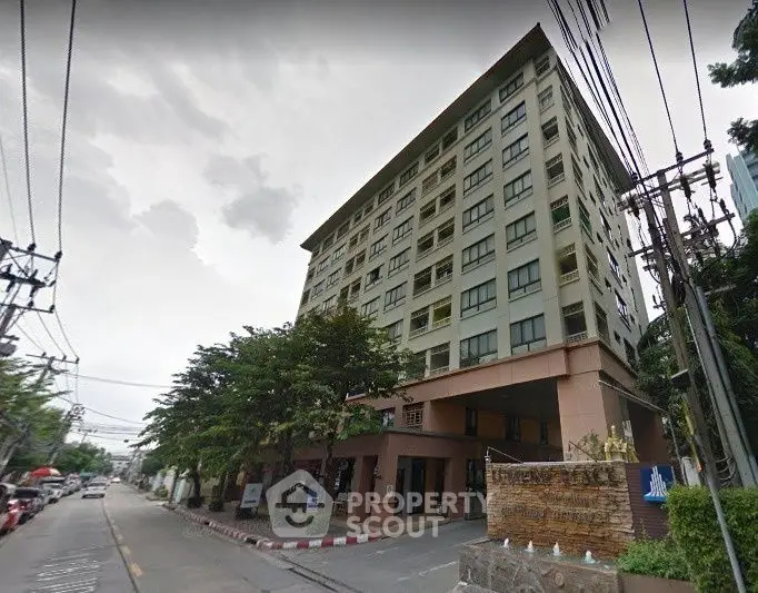Modern urban apartment building with street view and lush greenery.