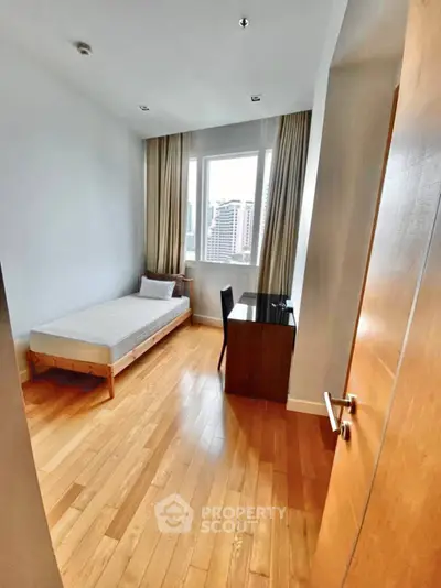 Cozy bedroom with wooden flooring and city view, ideal for urban living.