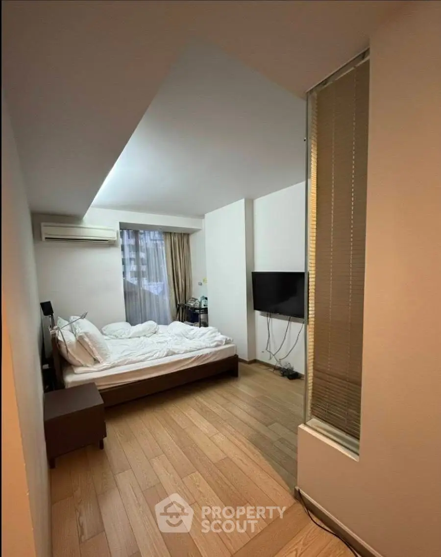 Cozy bedroom with modern design, featuring a comfortable bed, wall-mounted TV, and air conditioning unit.