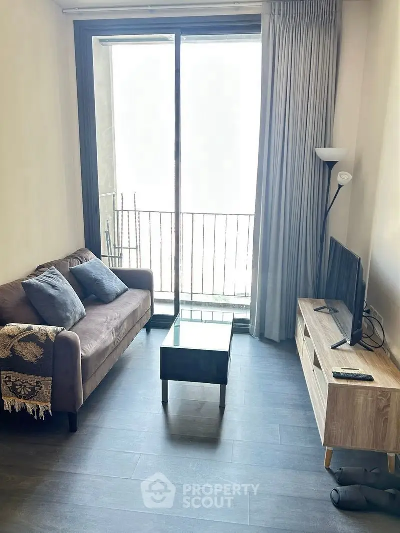 Cozy living room with modern decor and balcony access in urban apartment.