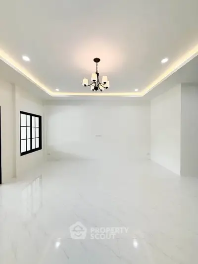 Spacious modern living room with elegant chandelier and white marble flooring.