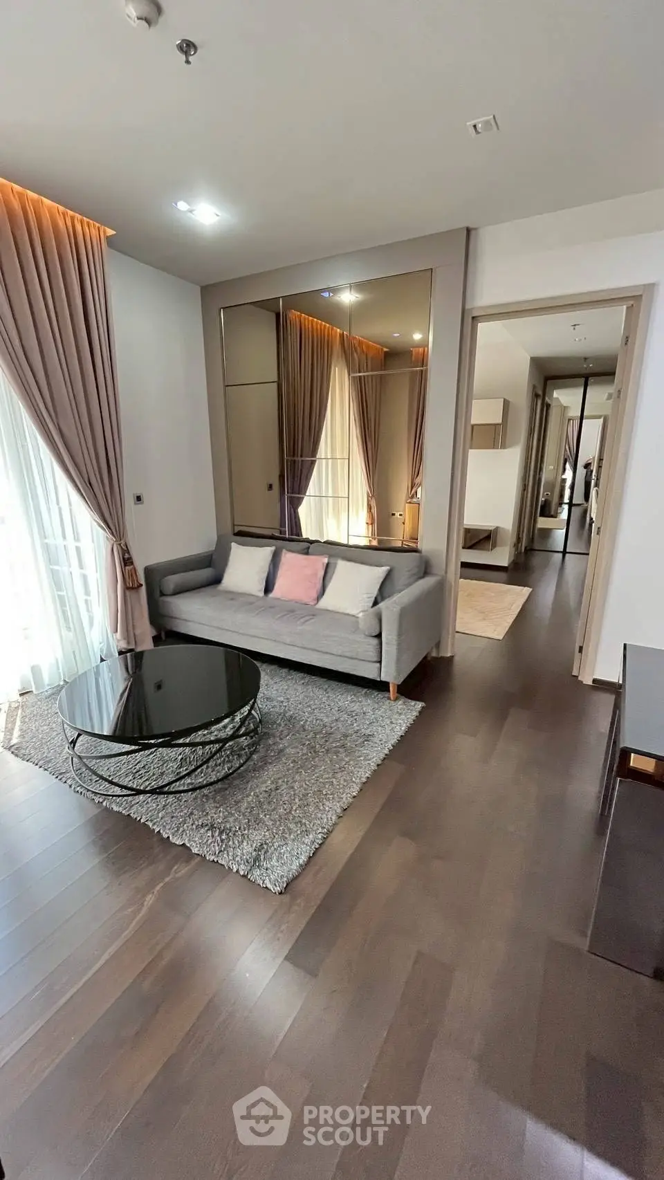 Modern living room with elegant decor and natural light, featuring a stylish sofa and glass coffee table.